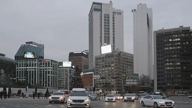 차들이 신호를 기다리는 혼잡한 교차로 위로 솟은 사무용 빌딩